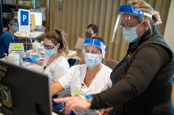 A clinical instructor helps a student at a vaccine clinic.